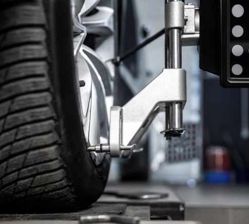 Precision Wheel Alignment in Buffalo, NY​. Close-up car wheel indoors service maintenance repair center against laser sensor equipment diagnostics and 3d wheel alignment. Vehicle inside garage workshop for auto camber toe check fixing work