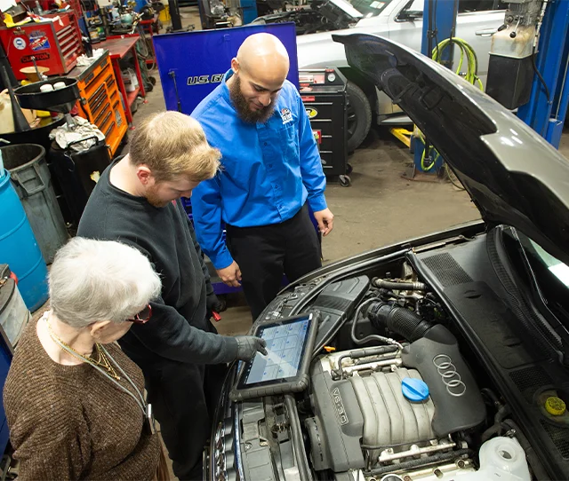 Client and two total automotive employee reviewing diagnostic of the client's car