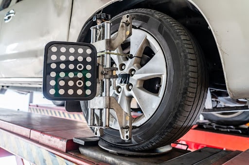 Winter Wheel Alignment: Why Buffalo Drivers Need It for Safe Winter Roads with Total Automotive in Buffalo, NY. Image of white car on the alignment machine in the shop.