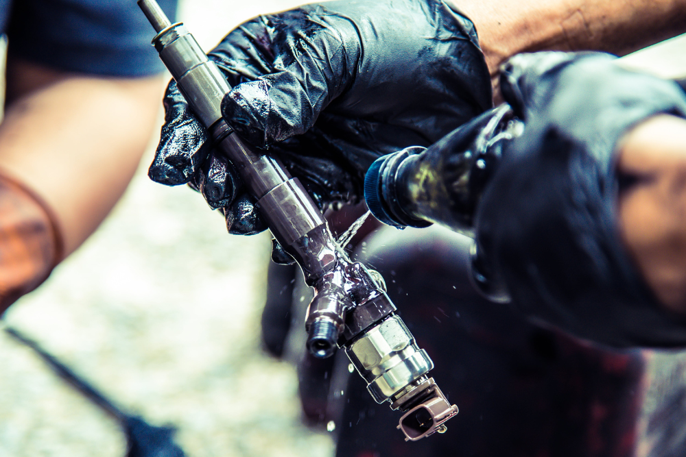 fuel injection cleaning, auto repair in Buffalo, NY at Total Automotive. Diesel technician cleaning a fuel injector with gloves on, highlighting the precision and care involved in diesel injector maintenance and repair.