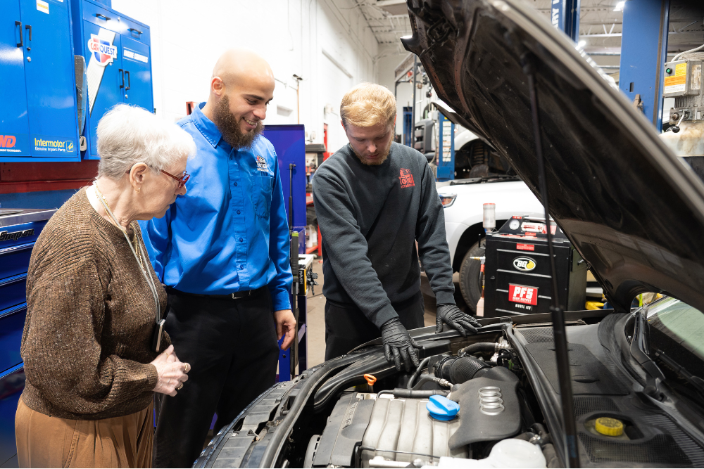 great mechanic, auto repair in Buffalo, NY at Total Automotive. Service advisor and technician explaining engine issues to a customer, showcasing transparency, trust, and professional vehicle care.