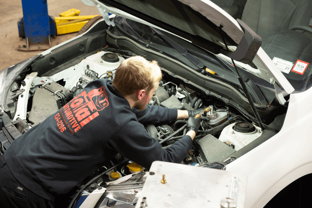 Auto repair in Buffalo, NY by Total Automotive. Image of a technician inspecting engine components under the hood of a vehicle, highlighting accurate diagnostics, preventative maintenance, and dependable automotive repair services.