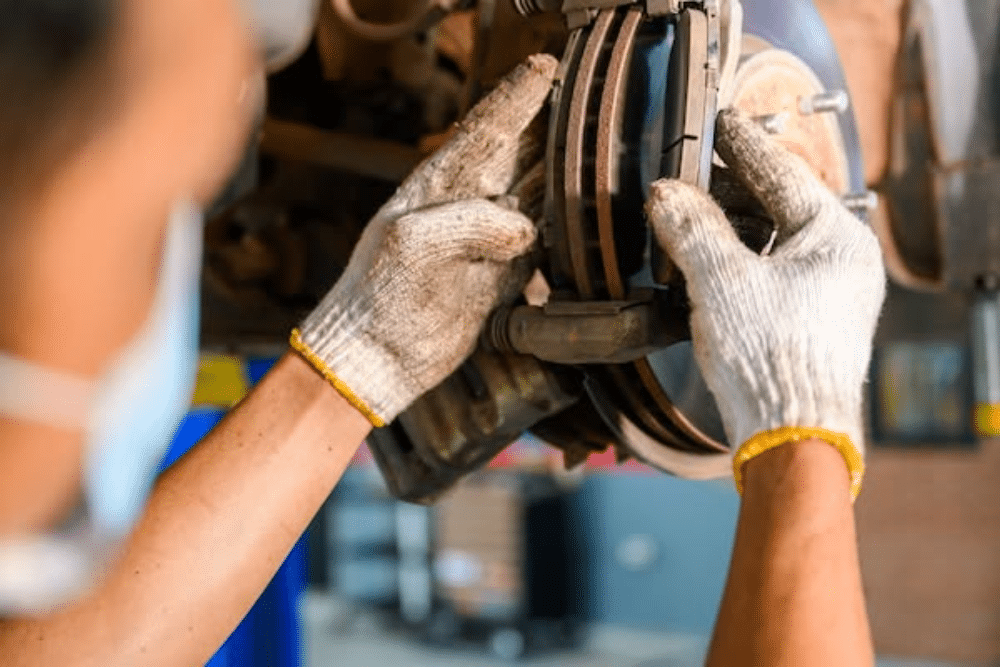 NY State Inspection and Brake Service in Tonawanda, NY At Total Automotive. Image of Technician checking brake rotor and pad wear during vehicle safety check